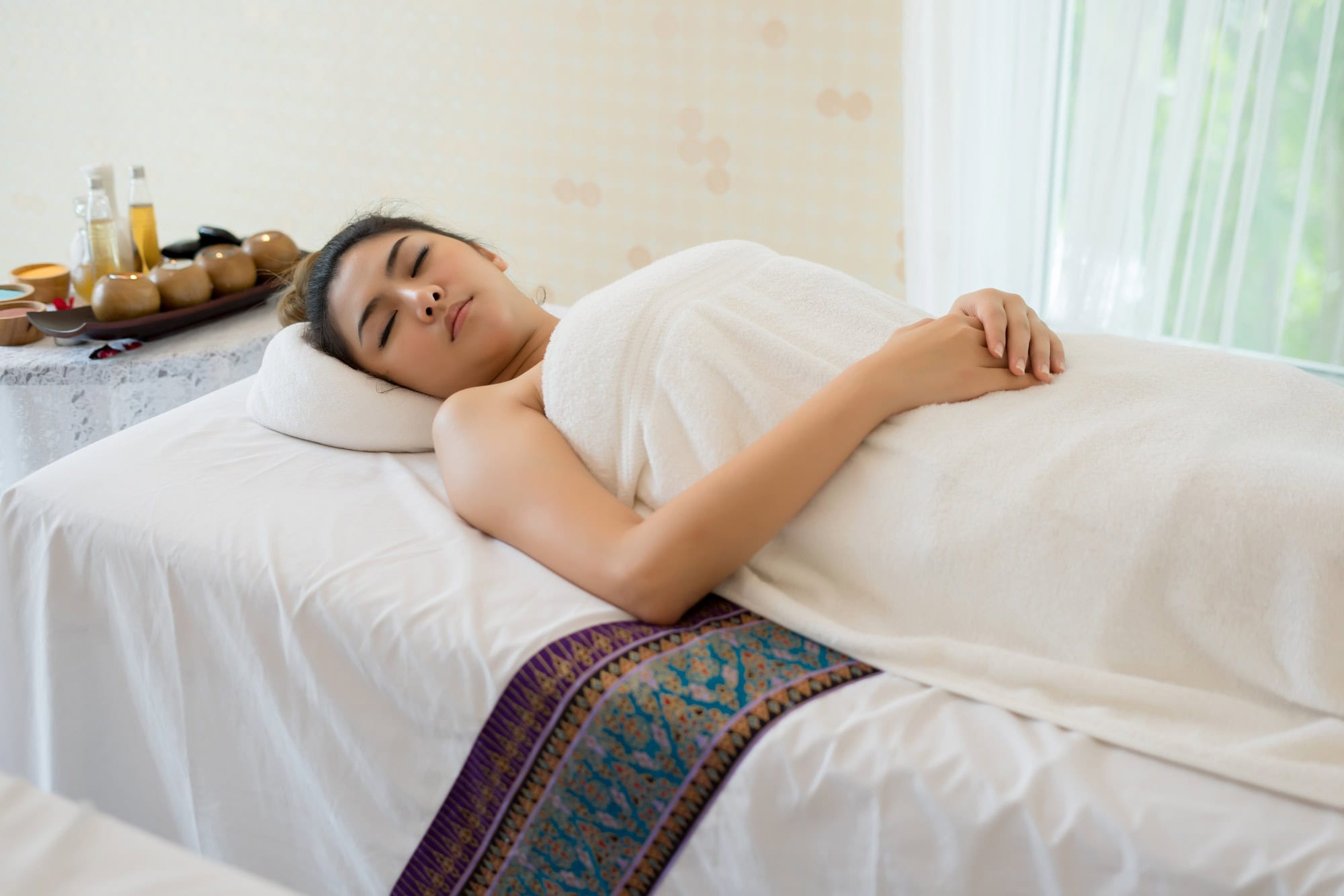Beautiful smiling woman with flowers resting in the spa before massage.