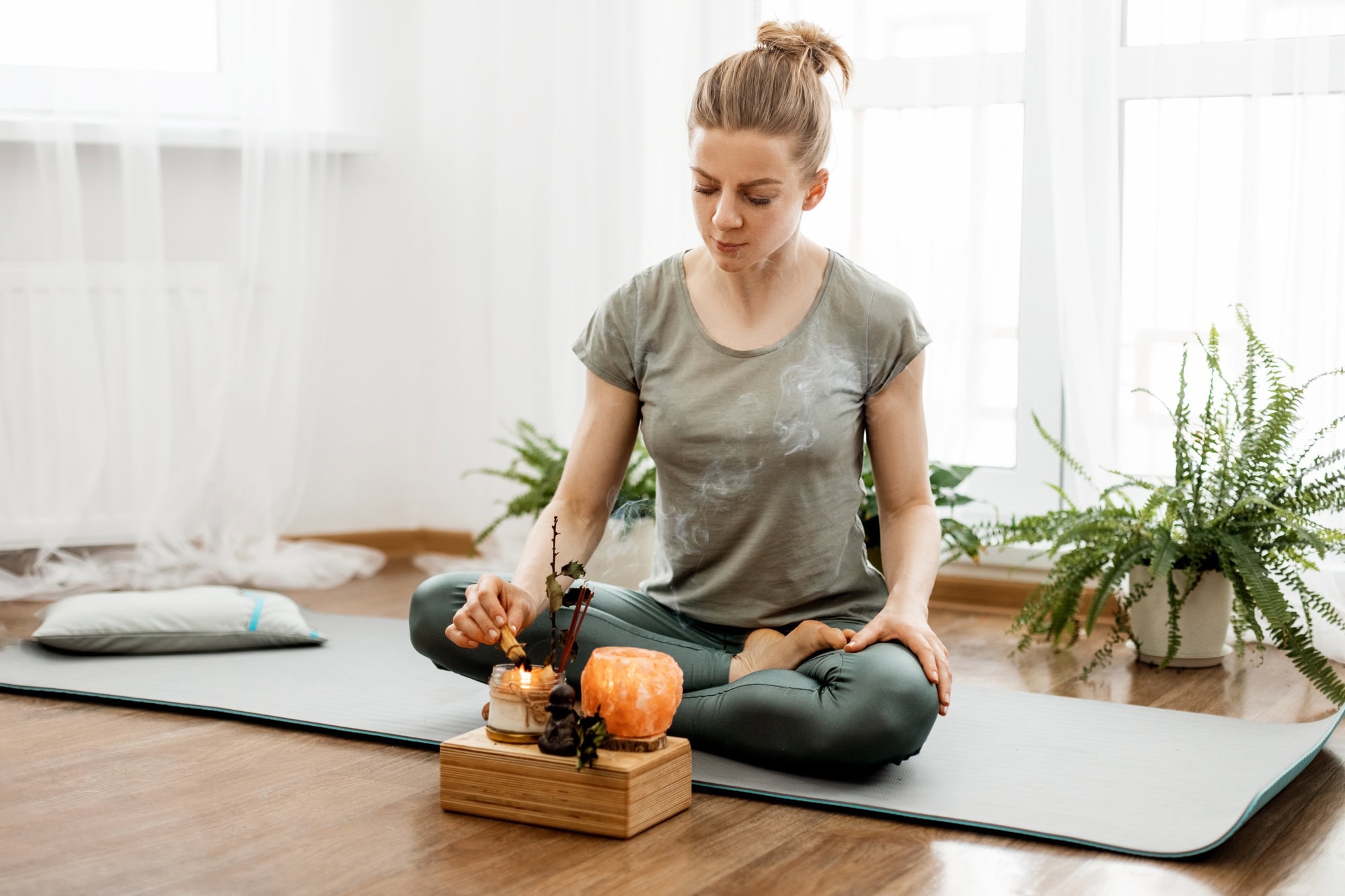 Young relaxed woman doing yoga at home with candles and incense